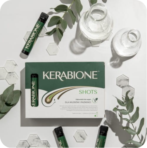 Opakowanie Kerabione Shots i ampułki z suplementem ułożone na jasnym tle wśród zielonych liści i szklanych naczyń laboratoryjnych, tworzących estetyczną kompozycję inspirowaną naturą i pielęgnacją włosów oraz paznokci.